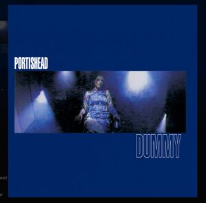 Albumcover von Portishead Dummy mit blauem Hintergrund, weißem Schriftzug und dunkler filmischer Szene im Zentrum.