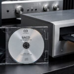 SACD im Jewelcase vor einem hochwertigen SACD-Player mit geöffneter Disc-Schublade