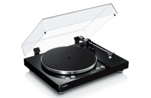 Yamaha MusicCast Vinyl 500 in Schwarz mit geöffneter Staubschutzhaube, Plattenteller und geradem Tonarm in Schrägansicht.