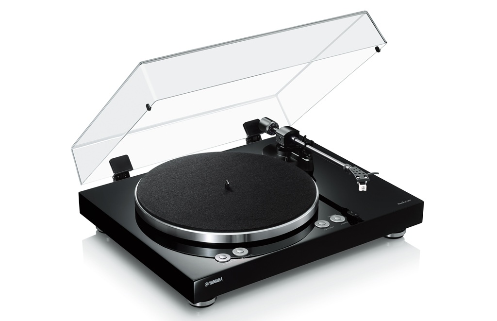 Yamaha MusicCast Vinyl 500 in Schwarz mit geöffneter Staubschutzhaube, Plattenteller und geradem Tonarm in Schrägansicht.